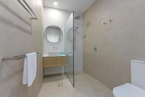 a bathroom with a glass shower and a sink at Mandalay Luxury Beachfront Apartments in Port Douglas