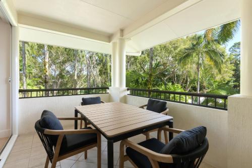 a balcony with a wooden table and chairs at Mandalay Luxury Beachfront Apartments in Port Douglas