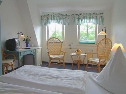 a bedroom with chairs and a table and a bed at Hotel Gastmahl des Meeres in Sassnitz