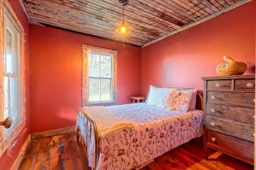 a bedroom with red walls and a bed and a dresser at Historic Cabin with Porch and Firepit 5 Minutes from Bryson City in Bryson City