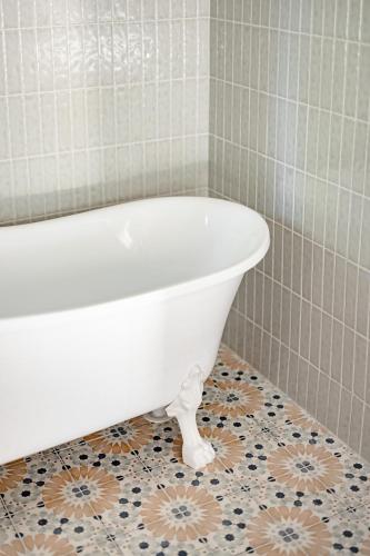 a bathroom with a white bath tub on a tile floor at The Wellness Farm Broke in Broke