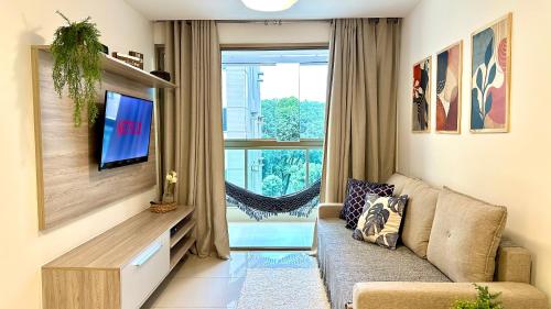 a living room with a couch and a tv and a window at Blue Hope by Mosaico Stays in Vitória