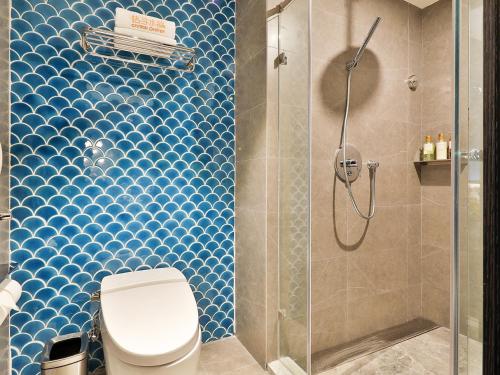 a bathroom with a toilet and a shower with blue tiles at 上海五角场桔子水晶酒店 in Shanghai