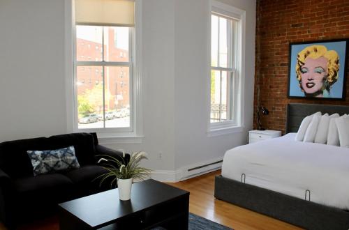 a bedroom with a white bed and a couch and windows at Stylish Downtown Studio in the SouthEnd, C.Ave# 3 in Boston
