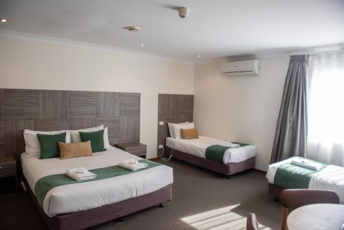 a hotel room with two beds and a window at Victoria Hotel Strathalbyn in Strathalbyn