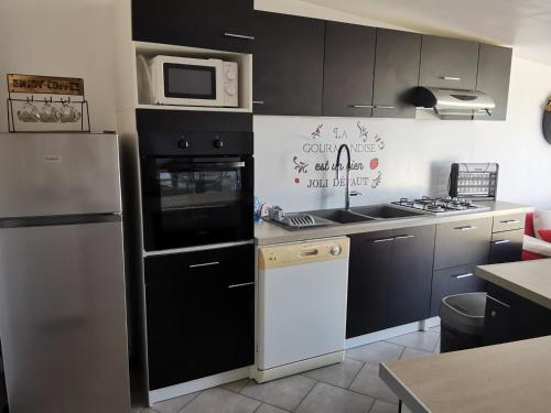 a kitchen with black cabinets and a white refrigerator at Maison calme avec clim, WIFI, jardin et vue sur le Lay - FR-1-194-274 in LʼAiguillon-sur-Mer
