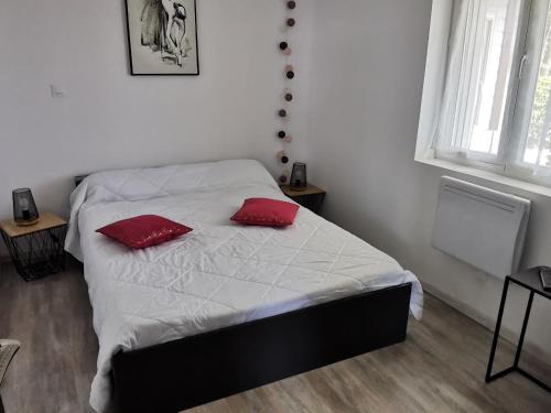 a bedroom with a bed with two red pillows on it at Maison calme avec clim, WIFI, jardin et vue sur le Lay - FR-1-194-274 in LʼAiguillon-sur-Mer