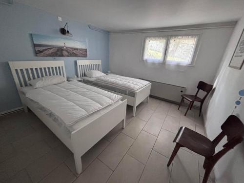 - une chambre avec 2 lits et une chaise dans l'établissement Maison rénovée 3 chambres près de l'océan avec jardin fermé et WiFi - FR-1-194-290, à La Faute-sur-Mer