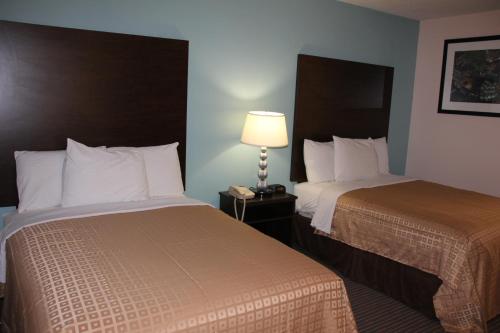 a hotel room with two beds and a lamp at Sterling Inn near IAG Airport in Niagara Falls