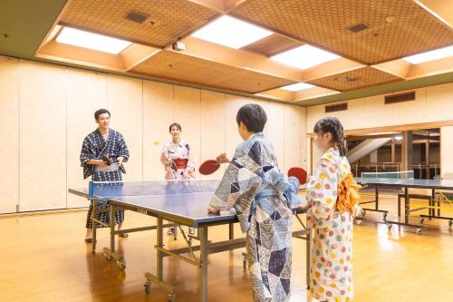 a group of children standing around a ping pong table at Ooedo Onsen Monogatari Premium Hotel New Shiobara in Nasushiobara