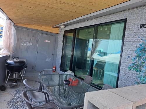 a patio with a glass table and chairs and a grill at Narae House in Busan