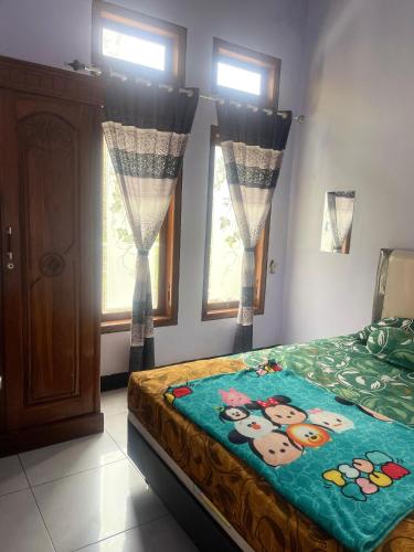 a bedroom with a bed and two windows at mas dylan homestay in Probolinggo
