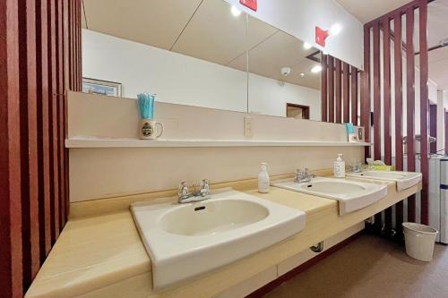 a bathroom with two sinks and a large mirror at Pension Asuka inn Daisen in Hoki