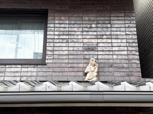 a statue sitting on the side of a building at Rinn Sanjo Ohashi East in Kyoto