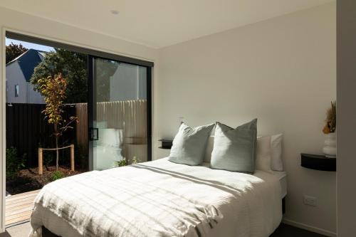 a bedroom with a white bed and a large window at New Three Bedroom Townhouse - Walk to the CBD! in Christchurch
