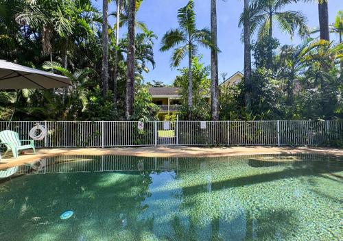 a swimming pool with a fence and palm trees at Liana One Coastal Mission Vibe two bedroom apartment in Mission Beach