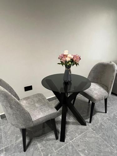 two chairs and a table with a vase of flowers on it at Licious Homes 1 in Nalakonge