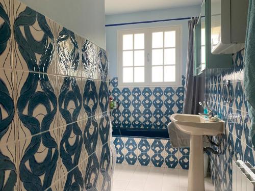 La salle de bains est pourvue de murs carrelés bleus et blancs et d'un lavabo. dans l'établissement Maison bord de mer calme à Jard-sur-Mer avec grand jardin clos - FR-1-336-162, à Jard-sur-Mer