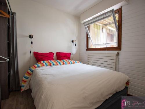 une chambre avec un lit avec des oreillers rouges et une fenêtre dans l'établissement Charmant T2 à 50m de la plage avec balcon et wifi - FR-1-825-40, à La Rochelle