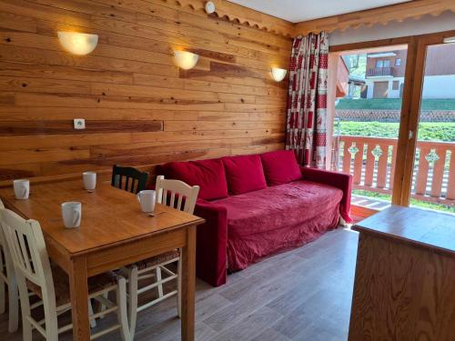 un salon avec un canapé rouge et une table dans l'établissement Location saisonnière à Saint-François-Longchamp pour 8 personnes - FR-1-807-132, à Saint-François-Longchamp