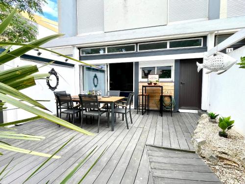 une terrasse en bois avec une table et des chaises dessus dans l'établissement Maison moderne proche plage avec patio et parking privatif - FR-1-748-32, à Canet