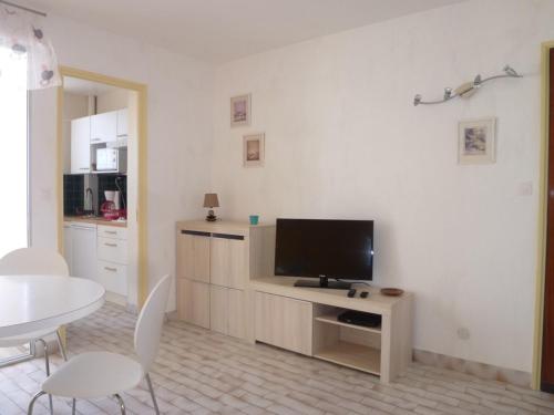 un salon avec une télévision et une table avec des chaises dans l'établissement Deux-pièces rénové face mer avec parking, 4 pers - FR-1-750-100, à Canet