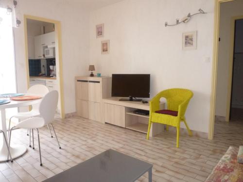 un salon avec une télévision, une table et des chaises dans l'établissement Deux-pièces rénové face mer avec parking, 4 pers - FR-1-750-100, à Canet