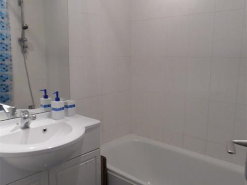 une salle de bain blanche avec un lavabo et une baignoire dans l'établissement Charmant 2 Pièces Proche Plage avec Parking Privé - FR-1-750-102, à Canet