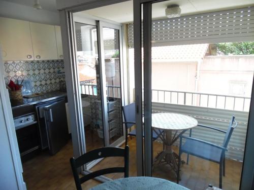 d'une cuisine avec une table et des chaises sur un balcon. dans l'établissement Deux-Pièces Front de Mer pour 4 Pers à Canet-Plage - FR-1-750-107, à Canet