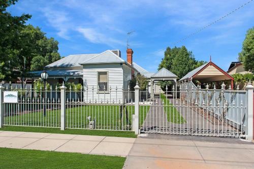a white fence in front of a white house at Francis Retreat- Echuca Holiday Homes in Echuca