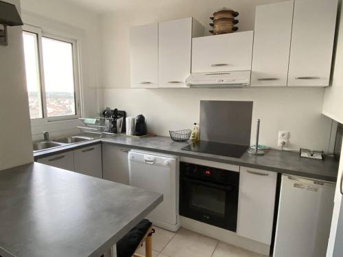 une cuisine avec des appareils blancs et un comptoir noir dans l'établissement Deux-pièces 5 pers, centre-ville, vue montagne, plage à 150m - FR-1-750-108, à Canet