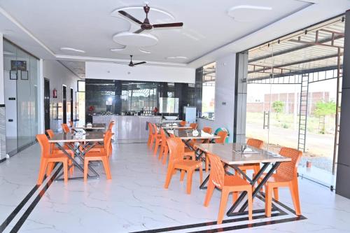 une salle à manger avec tables, chaises et fenêtres dans l'établissement Hotel Rudraksha Restaurant And Resort, à Khātu