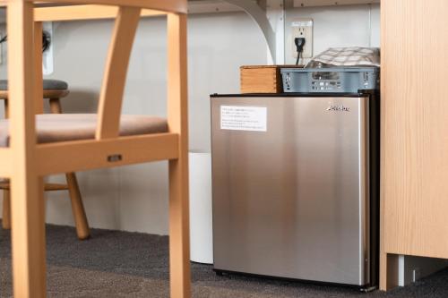 a silver refrigerator next to a wooden chair at Hotel Naranohamori in Nara