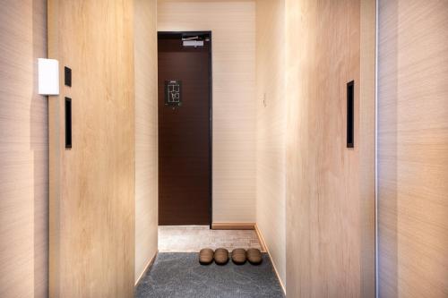 a hallway with wooden walls and a black door at Hotel Naranohamori in Nara