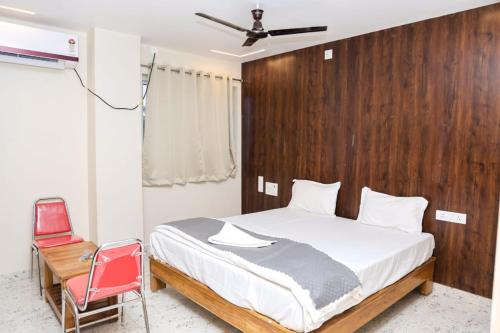 a bedroom with a bed and a red chair at Rama grand in Tirupati
