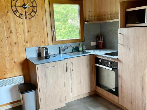 une cuisine avec un évier et une horloge murale dans l'établissement Chalet atypique plein de charme avec garage et balcon, idéal pour familles - FR-1-761-33, à Villard-de-Lans