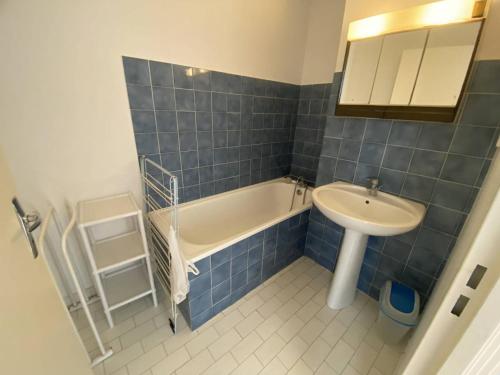 une salle de bain carrelée bleue avec un lavabo et une baignoire dans l'établissement Charmant deux-pièces sud avec terrasse vue mer à Canet-Plage - FR-1-750-113, à Canet