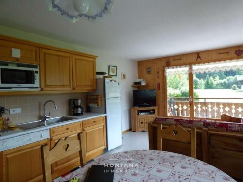 une cuisine avec des armoires en bois et un réfrigérateur blanc dans l'établissement Appartement lumineux près des pistes, 3 chambres, 7 personnes - FR-1-458-216, au Grand-Bornand