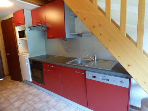 une cuisine avec des armoires rouges et un évier dans l'établissement Charmant appartement 6 pers avec balcon sud au Grand-Bornand - FR-1-458-222, au Grand-Bornand