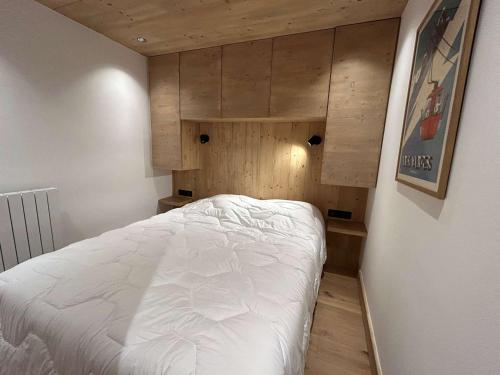 - une petite chambre avec un lit blanc et des murs en bois dans l'établissement Appartement rénové Méribel, proche pistes, fibre incluse - FR-1-180-657, à Les Allues