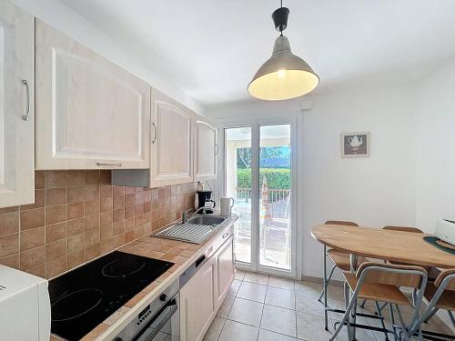 une cuisine avec des armoires blanches et une table en bois dans l'établissement Appartement paisible à 100m de la plage, avec jardin - FR-1-770-50, à Saint-Cyr-sur-Mer