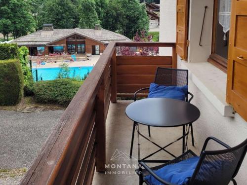 d'un balcon avec une table et des chaises, ainsi que d'une piscine. dans l'établissement Beau 2 pièces au cœur du Grand-Bornand, pour 4 personnes - FR-1-458-219, au Grand-Bornand