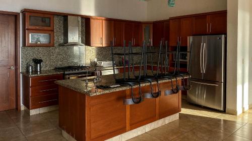a kitchen with wooden cabinets and a stainless steel refrigerator at MARACUYA at Limoncito Beach in Limoncito Hill