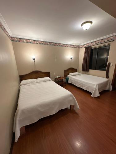 a hotel room with two beds and a television at Hotel & Suites El Quijote in Cuenca