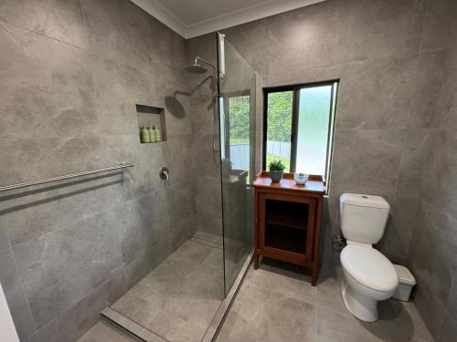 a bathroom with a toilet and a glass shower at Jabiru Stay Daintree Village in Daintree