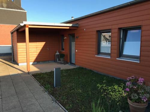 a house with a red wall and a patio at Ferienwohnung "Seglersteg, Bungalow 11" Hafenspitze in Eckernförde