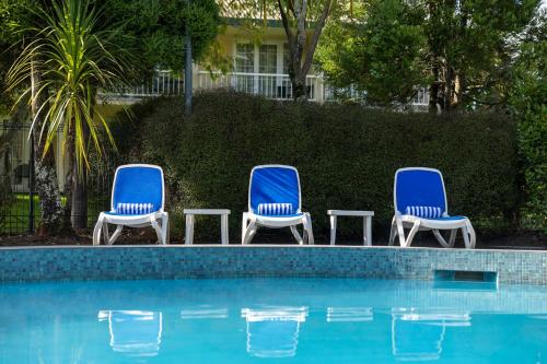 three blue chairs sitting next to a swimming pool at Wairakei Resort Taupo in Taupo
