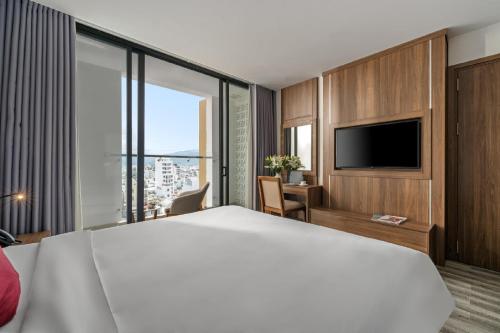 a hotel room with a large bed and a television at Astica Hotel Nha trang in Nha Trang