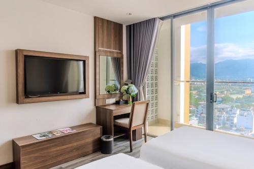 a hotel room with a desk and a tv and a bed at Astica Hotel Nha trang in Nha Trang