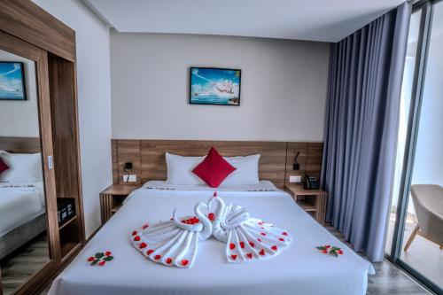 a bedroom with a white bed with red pillows at Astica Hotel Nha trang in Nha Trang